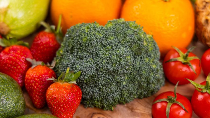 A vibrant collection of fresh, organic fruits and vegetables on a wooden table, showcasing healthy variety.